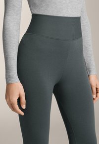 Magas derekú, sötétzöld bordázott leggings, sima textúrával. A testhez álló kialakítás kiemeli az alakot, varrat nélküli derékkal rendelkezik.