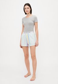 Grijze T-shirt met korte mouwen, gecombineerd met gestreepte shorts in meerdere kleuren met een witte elastische tailleband met logo. Gemaakt van katoen, relaxed fit.