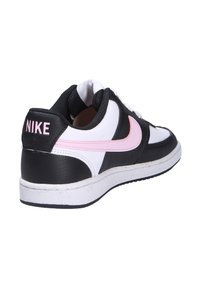 Zapatilla Nike en blanco y negro con acentos en rosa, cuero texturizado, cuello acolchado, diseño de cordones y suela de goma blanca.