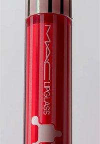 MAC Lipglass i en cylindrisk, transparent ljusröd förpackning med silverdetaljer. Har logotyp och vit design på den nedre delen.