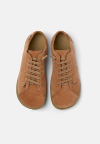 Brown suede sneakers with rounded toes, six lace eyelets, and tonal laces. Flat soles with minimal tread. Soft inner lining.