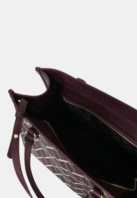 Borsa bordeaux con un motivo geometrico bianco, dotata di un ampio interno nero, tasca con zip e due tracolle.