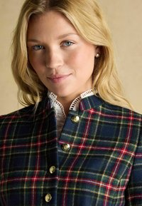 Tartan jacket made of wool, featuring a navy base with red and green lines, gold buttons, and a white ruffled collar underneath.