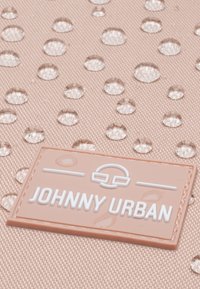 Vízlepergető barack szövet v�ízcseppekkel rendelkezik. Egy téglalap alakú gumi címke, amelyen fehér színnel van megpréselve a "JOHNNY URBAN" felirat, az alján, jobb oldalon található.