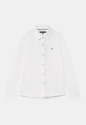 Weißes langärmliges Hemd mit Knopfleiste und Kragen, kleinem Tommy Hilfiger-Logo auf der linken Brust und sichtbarem Markenetikett am inneren Kragen.