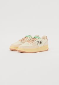 Sneakers Lacoste in tonalità crema e pesca con suola in gomma, lacci verdi e logo coccodrillo ricamato di lato.