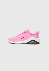 Chaussure de sport Nike rose avec tige en maille, logo noir, semelle intermédiaire blanche et semelle extérieure en caoutchouc. Dispose d'un col rembourré et d'un design à lacets.