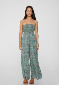 Mono sin tirantes con un estampado floral en tonos de azul, rosa y verde; cuerpo fruncido, pantalones anchos y tela ligera.
