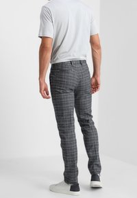 Grijze geruite broek met slanke pasvorm, gemaakt van gladde stof. Kenmerkt zich door een klassiek patroon en wordt gecombineerd met witte sneakers.
