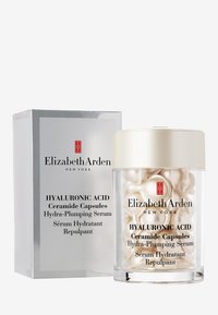 Hyaluronsyra Ceramidkapslar i en genomskinlig burk med ett gyllene lock, som innehåller glansiga, pärlliknande kapslar. Förpackningen har silverdetaljer och text.