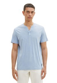 Chemise henley à manches courtes bleu clair fabriquée en coton doux, dotée d'un col en V et d'une patte de trois boutons, avec une coupe décontractée.