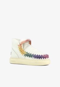 Botas de cuero blancas con acentos trenzados coloridos en amarillo, verde, rosa y morado. Forro suave y suela de goma color crema. Forma clásica.