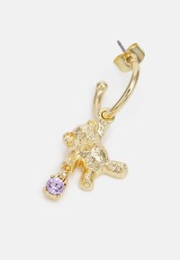 Brinco de argola em ouro com um charme em forma de urso de pelúcia texturizado segurando uma pedra preciosa roxa. O design é divertido e tridimensional.
