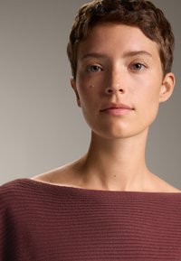 Burgundska rebrovana pulover z dizajnom brez naramnic. Pomanjšan pogled, ki poudarja teksturo, barvo in podrobnosti izrezane vrhnje polovice.