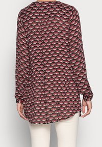 Rode en zwarte geblokte blouse met lange mouwen en een ronde onderrand, versierd met waaier-vormige motieven in het wit. Lichtgewicht stof met een gladde textuur.