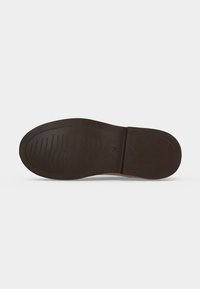 Semelle unique de chaussure marron foncé avec motif de bande de roulement et marquage taille 28, vue de dessous sur un fond clair uni.