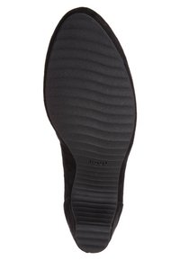 Svart mockaskor med en texturerad svart gummisula, försedd med ett vågigt mönster för bra grepp. En något rundad tådesign utan dekorativa accenter.