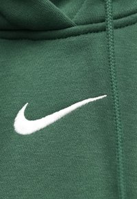 Casaco com capuz verde feito de tecido macio, apresentando um logotipo Nike swoosh branco bordado no peito, com acabamento texturizado e cordão ajustável.