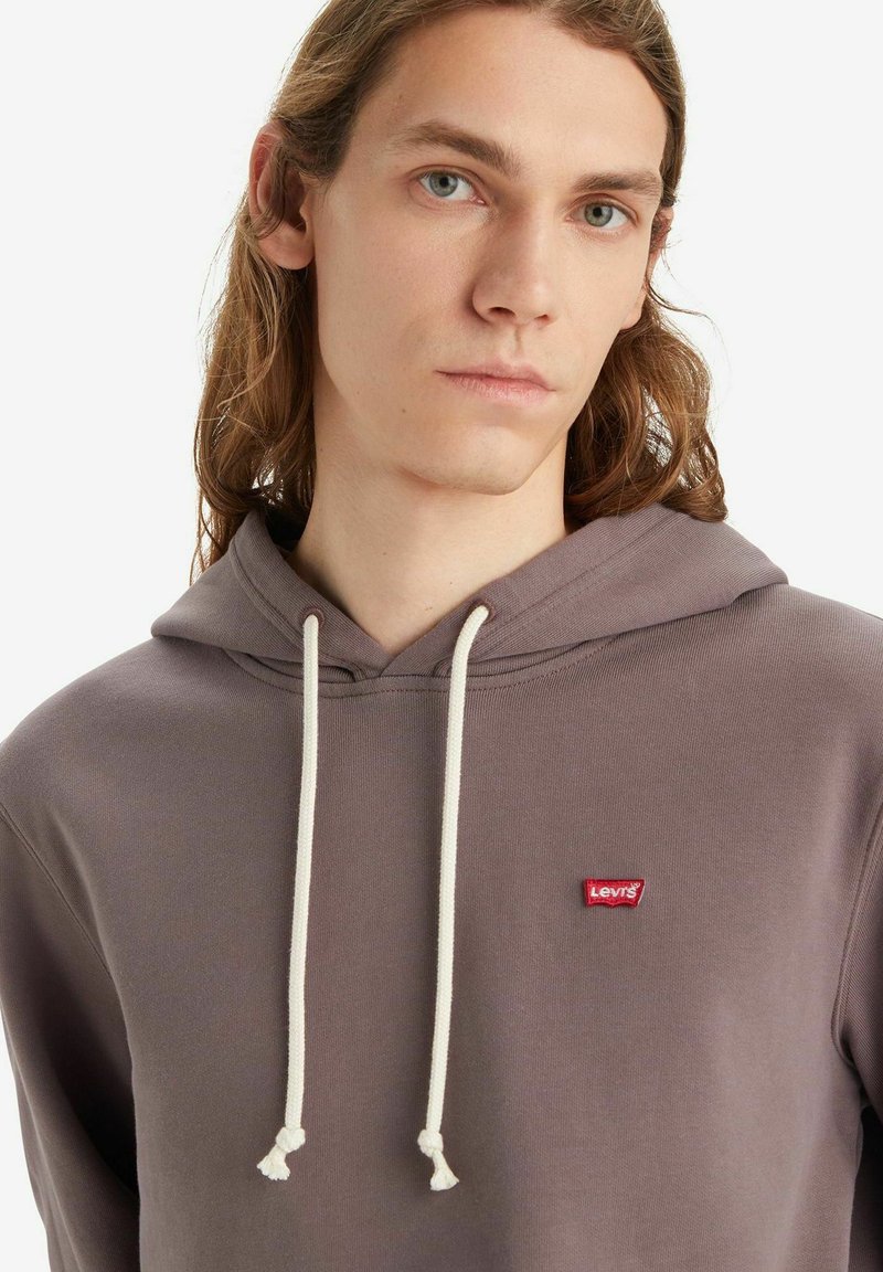 Sudadera con capucha gris con cordones blancos y un pequeño logotipo rojo de Levi's en el pecho. Textura suave, diseño casual.