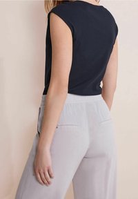 Námořnický pruhovaný top s krátkými rukávy, kombinovaný se světlými šedými kalhotami s bočními kapsami. Oblečení má uvolněný střih a jemnou texturu.