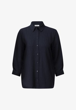 Camisa azul marino con tejido texturizado, botonadura frontal y cuello puntiagudo. Mangas largas con puños, corte relajado, acabado suave.