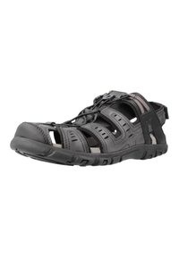 Mustad sandal sünteetilisest ülemisest, reguleeritava paeltesega sulgemise ja avatud disainiga. Omab lõikeid hingavuse tagamiseks ja tekstureeritud kummist tallat.