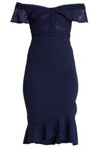 Mörkblå klänning utan axelband med spetsdetaljer och en figurnära design, med en volangnederdel för extra textur.