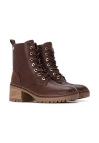 Botas de tobillo de cuero marrón con ojales dorados, diseño con cordones, tacón grueso con capas de acentos marrones y panel lateral texturizado.