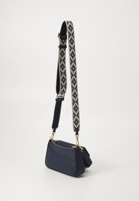 Sac en bandoulière en cuir marine avec une fermeture éclair dorée, doté d'une sangle ajustable à motif en crème et marine. Forme rectangulaire compacte.