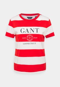 Punavalkoraidallinen lyhythihainen t-paita pyöreällä pääntiellä, jossa etupuolella teksti "GANT" ja pyöreä logo. Pehmeää puuvillamateriaalia.