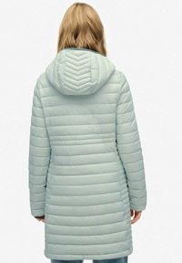 Lys grøn polstret frakke med hætte i chevron-mønster, lange ærmer og vandrette syninger, der når midt på låret.
