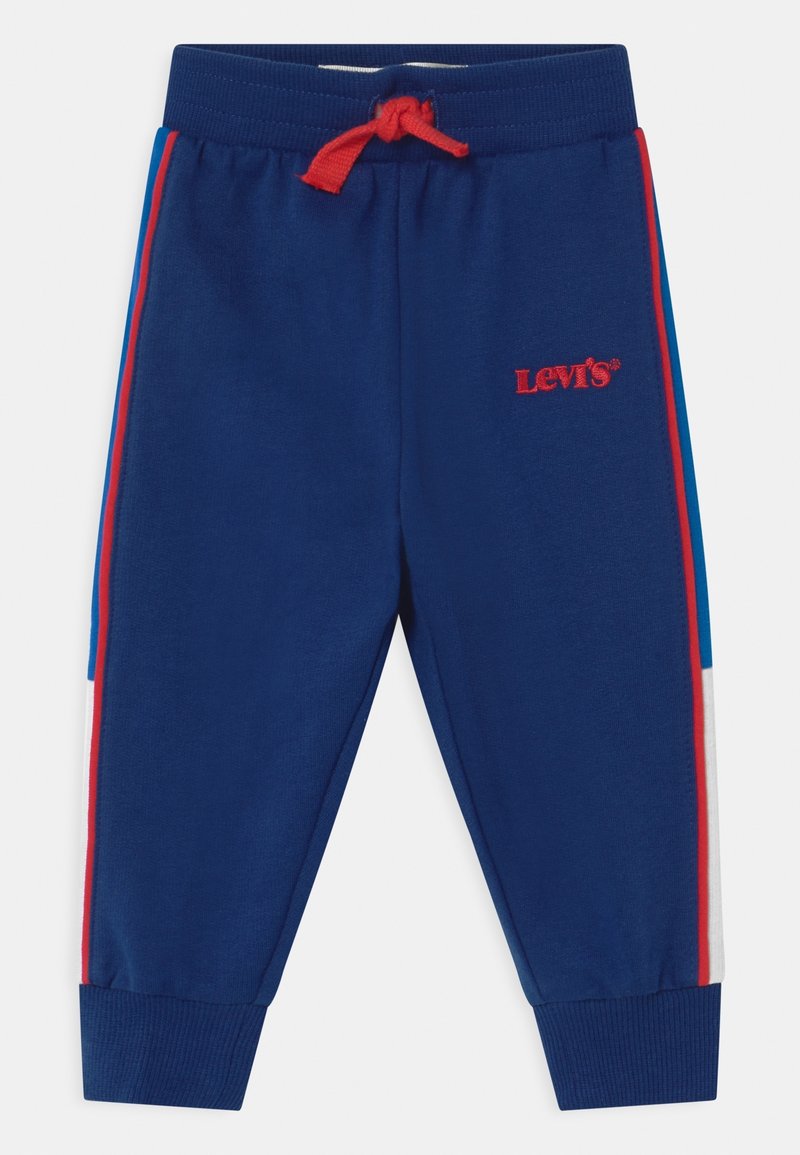 Námořnické tepláky s červeným stahováním, zdobené logem Levi's. Boční pruhy v červené a modré barvě. Manžety na kotnících a měkká textilie.