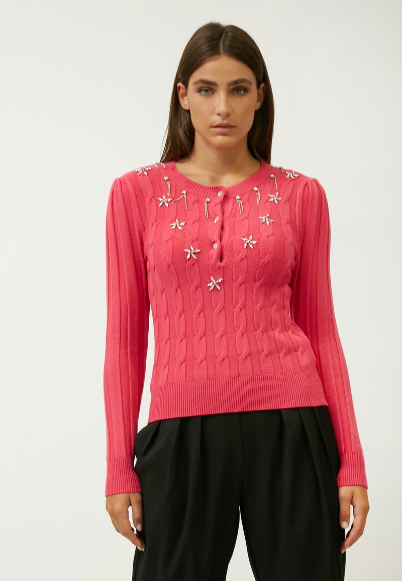 Gebreide, geribbelde, lange mouw trui in felroze met een knoopsluiting en florale versieringen over de voorkant.