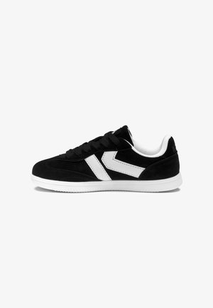 Sneaker nero basse con suola bianca e due strisce bianche a chevron sul lato, lacci neri e fodera interna bianca imbottita.