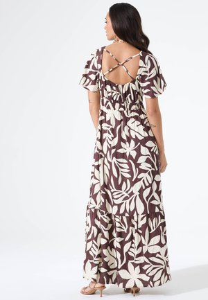 Vestido largo y fluido en marrón con patrones de hojas crema, con cintura fruncida, dobladillo de volantes y tirantes cruzados en la espalda. Tejido ligero.