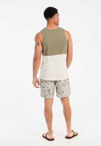 Top in maglia verde e bianca con sezione superiore uniforme e sezione inferiore a contrasto, abbinato a pantaloni corti con motivi a foglia.