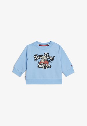 Sweatshirt azzurro chiaro con maniche lunghe, polsini e orlo a costine. Presenta una grafica frontale con la scritta "New York 1985 Hilfiger" insieme a un personaggio dei cartoni animati.