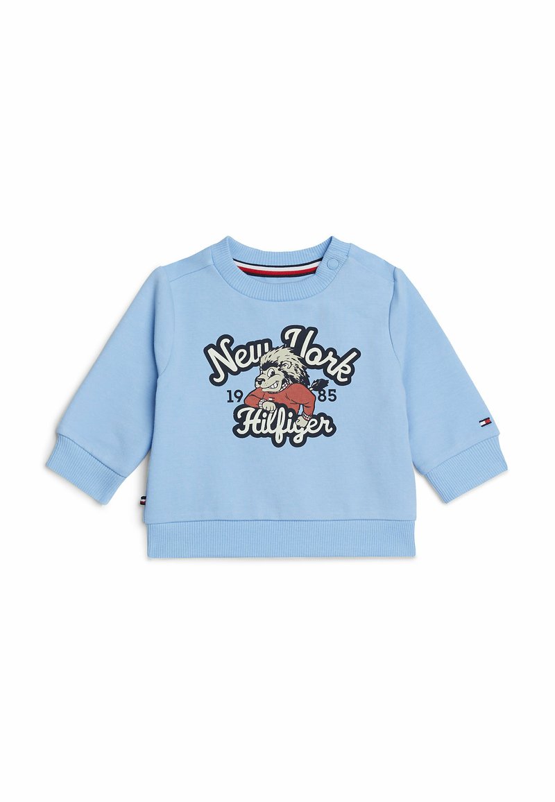 Sweatshirt azzurro chiaro con maniche lunghe, polsini e orlo a costine. Presenta una grafica frontale con la scritta "New York 1985 Hilfiger" insieme a un personaggio dei cartoni animati.