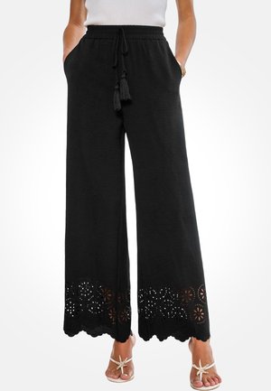Pantaloni neri a gamba larga con vita elastica, coulisse e nappe decorative. Motivo a fiori traforato con occhielli all'orlo.