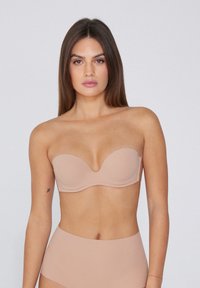 Naha strapless podprsenka se hladkými, tvarovanými košíčky a zaobleným výstřihem, se seamless okraji. V páru s béžovými kalhotkami s vysokým pasem.