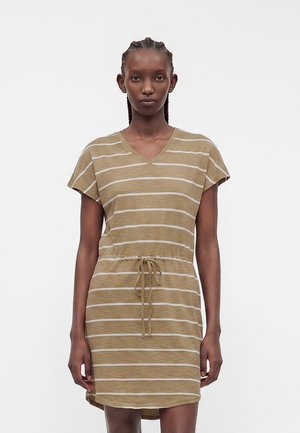 Frau mit geflochtenem Haar, die ein kurzärmeliges, beige-weiß gestreiftes Kleid mit V-Ausschnitt und Kordelzug in der Taille trägt, steht vor schlichtem Hintergrund.