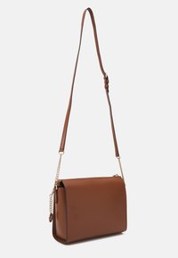 Brun läderväska med axelrem i justerbar längd och guldkedjeakcenter, uppvisad mot en vit bakgrund.