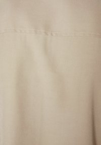 Beige fabric with a soft texture, featuring a subtle sheen and a horizontal seam across the middle. No patterns or hardware visible.