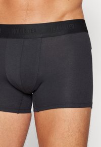 Schwarze Boxer-Shorts mit eng anliegender Passform, aus weichem Stoff gefertigt. Sie sind einfarbig, ohne Muster, und haben einen elastischen Bund mit Markenlogo.