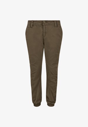 Szőke hajú fiú sötétkék kapucnis pulóverben, olívazöld melegítőnadrágban és fekete edzőcipőben áll egy világosszürke háttér előtt.