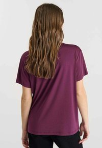 Korte mouwen, ronde hals t-shirt van donkerpaars stof. Gladde textuur met een subtiele glans en rechte zoom; losse pasvorm.