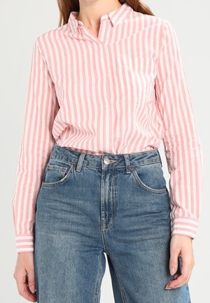 Camicia button-up a righe rosa chiaro e bianco con colletto e taschino singolo, abbinata a jeans in denim blu a vita alta.