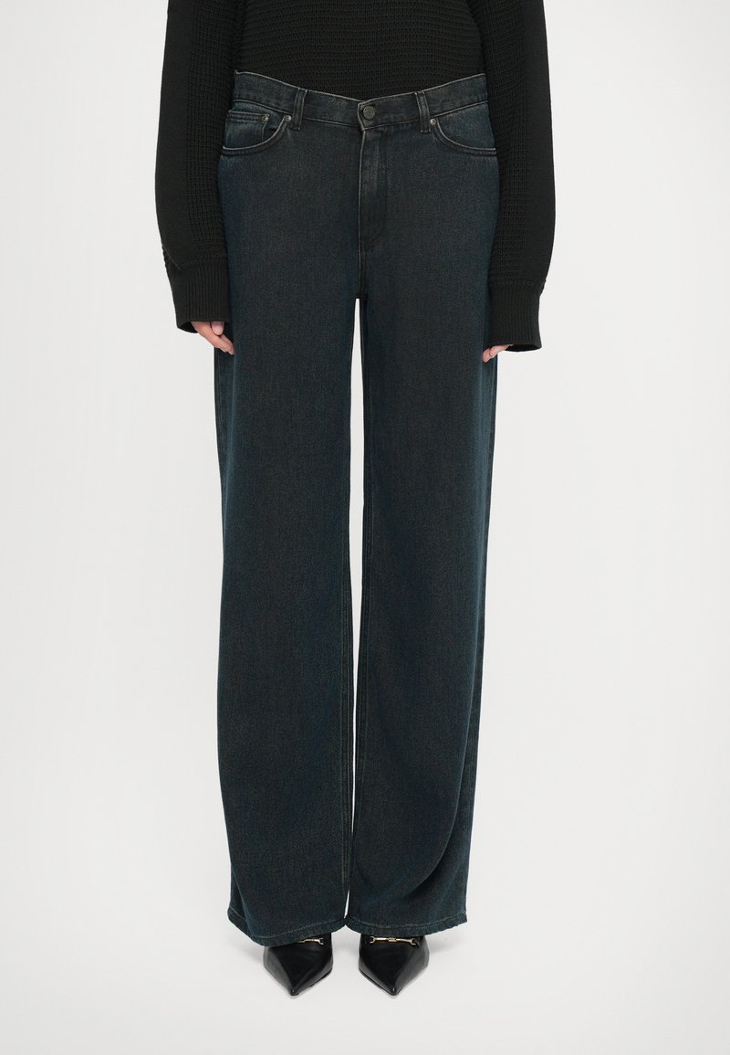 Jeans de mezclilla oscura de pierna ancha con cintura alta, que cuentan con una clásica cremallera y botón, desvanecidos sutiles y bolsillos traseros cosidos.
