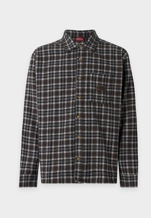 Chemise à manches longues boutonnée avec motif à carreaux noir, blanc et gris, poche poitrine et boutons marron.