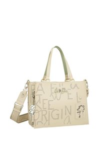 Bolso de mano beige con diseño de logo y texto perforados, asas duales, correa de hombro desmontable y un charm como acento. Material sintético suave.